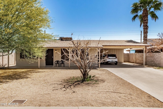 single story home featuring concrete driveway, fence, roof with shingles, and an attached carport