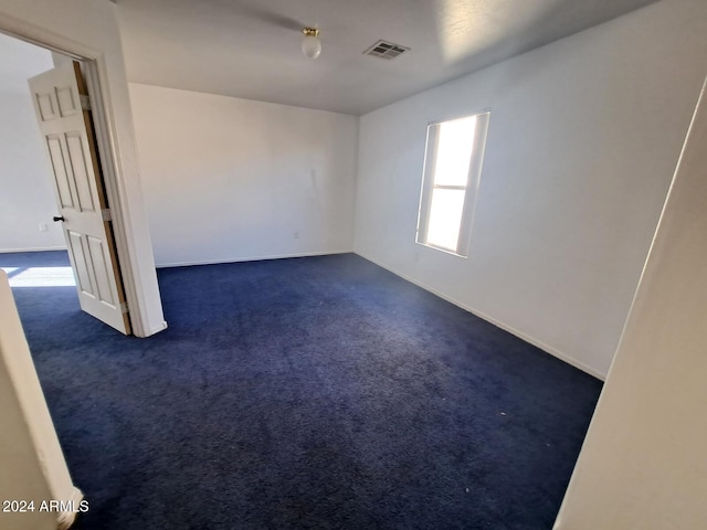 spare room featuring dark carpet