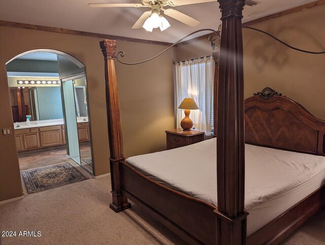 bedroom with ceiling fan, dark carpet, and ensuite bathroom