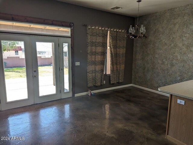 unfurnished dining area featuring french doors and a chandelier