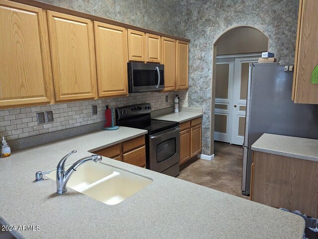 kitchen with appliances with stainless steel finishes, concrete floors, backsplash, and sink