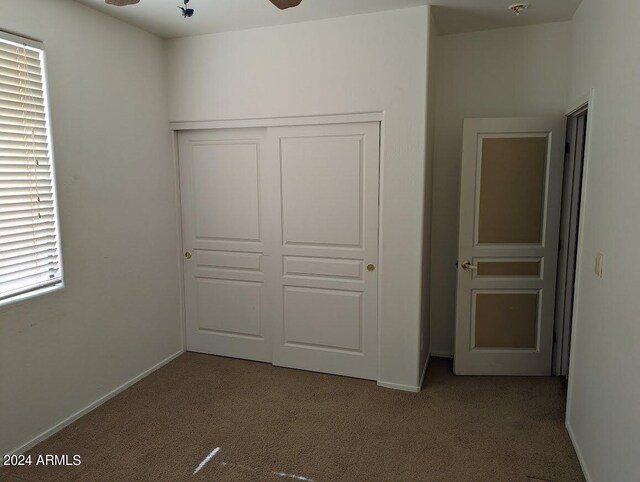 unfurnished bedroom with dark carpet, a closet, and ceiling fan