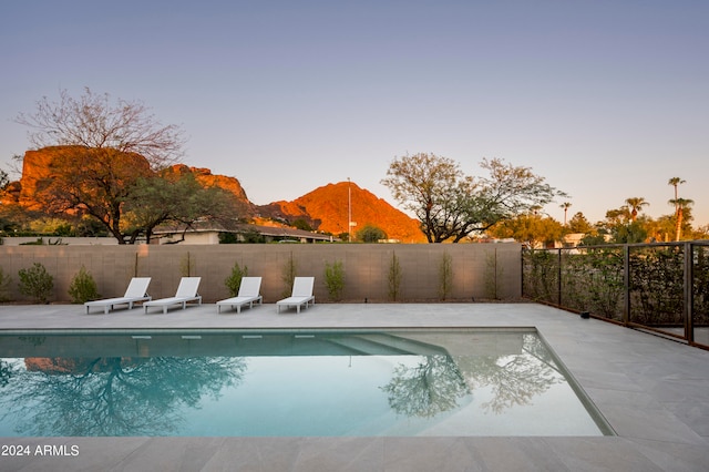 pool at dusk featuring a patio area and a mountain view