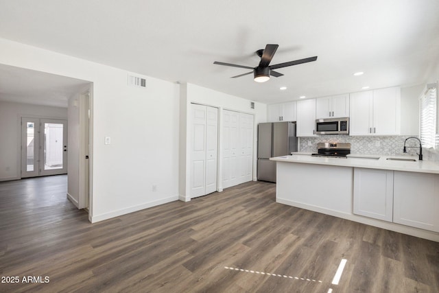 kitchen with a peninsula, a sink, visible vents, white cabinetry, and appliances with stainless steel finishes