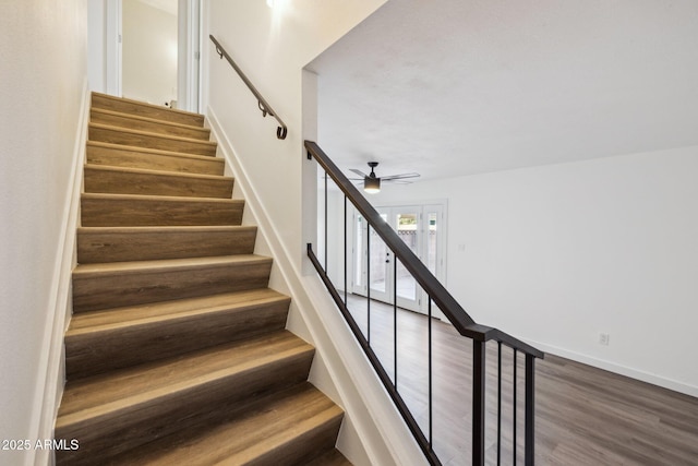 stairway with ceiling fan, baseboards, and wood finished floors