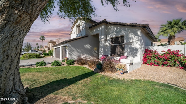 3411 S Vine St, Chandler, AZ 85248 - outdoor structure at dusk featuring an attached garage, driveway, fence, and a lawn