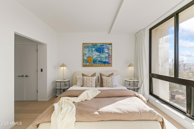 bedroom featuring light wood finished floors, baseboards, and floor to ceiling windows