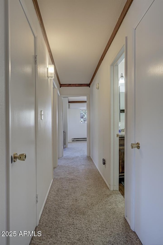 corridor featuring light colored carpet, crown molding, baseboards, and a baseboard radiator