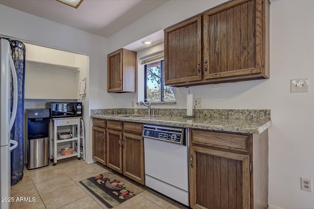 kitchen featuring a sink, light stone counters, freestanding refrigerator, light tile patterned flooring, and white dishwasher