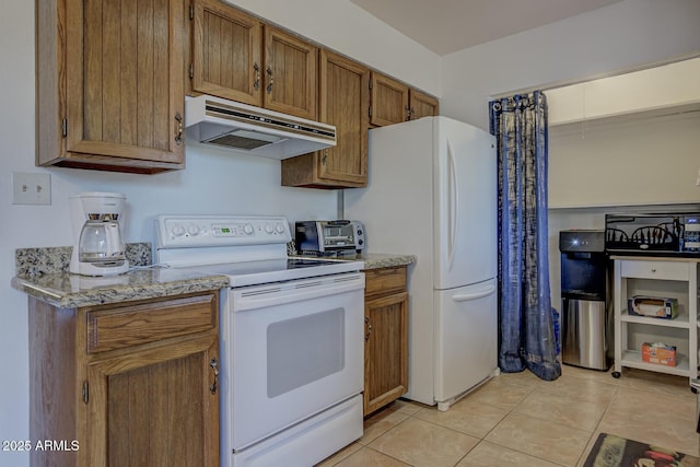 kitchen featuring brown cabinets, under cabinet range hood, light stone counters, white appliances, and light tile patterned floors