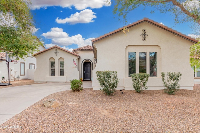 mediterranean / spanish home with stucco siding, driveway, and a tiled roof