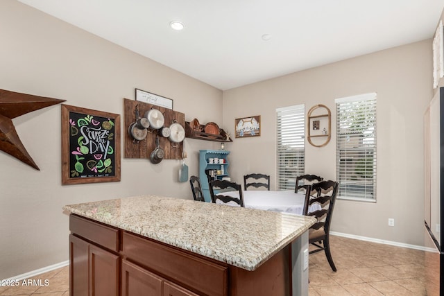 kitchen with light stone counters, baseboards, a kitchen island, and light tile patterned flooring