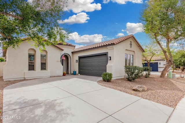 mediterranean / spanish-style house with a tile roof, an attached garage, driveway, and stucco siding