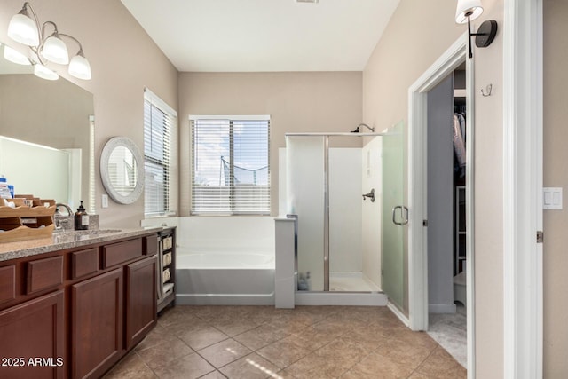 bathroom with a spacious closet, tile patterned flooring, a shower stall, a garden tub, and vanity