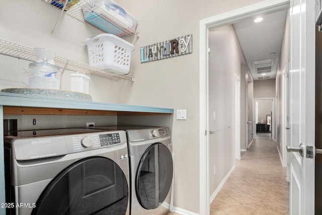 laundry area featuring light tile patterned floors, laundry area, washing machine and dryer, and baseboards