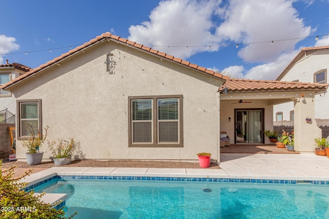 rear view of house with an outdoor pool, stucco siding, a patio, and a tiled roof