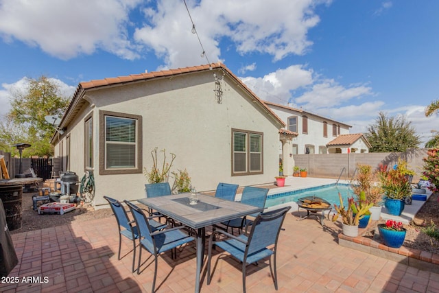 view of patio / terrace featuring outdoor dining space, a fenced in pool, a fire pit, and a fenced backyard