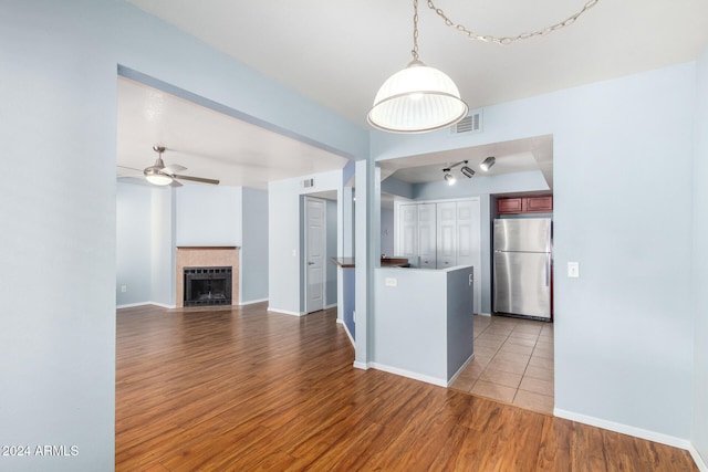 kitchen featuring kitchen peninsula, stainless steel fridge, hanging light fixtures, ceiling fan, and light hardwood / wood-style floors