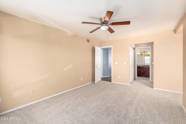 unfurnished bedroom featuring ensuite bath, light colored carpet, and ceiling fan