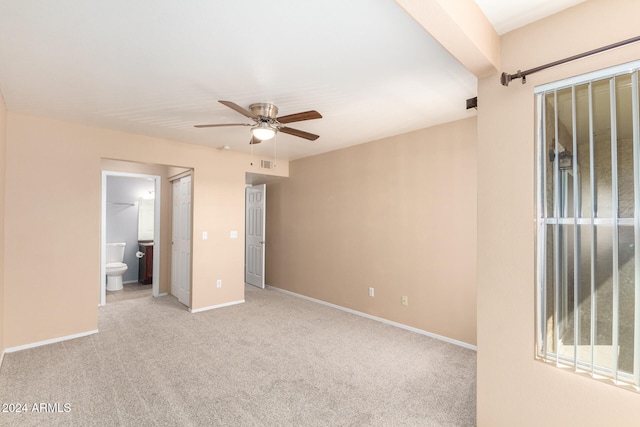 unfurnished bedroom with a closet, light carpet, a walk in closet, ensuite bath, and ceiling fan