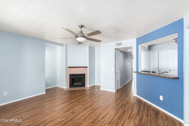 unfurnished living room with ceiling fan, a textured ceiling, and dark hardwood / wood-style floors