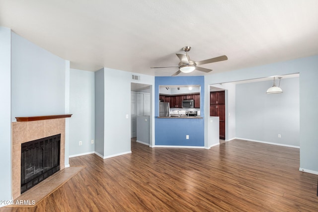 unfurnished living room with dark hardwood / wood-style floors, a tile fireplace, and ceiling fan