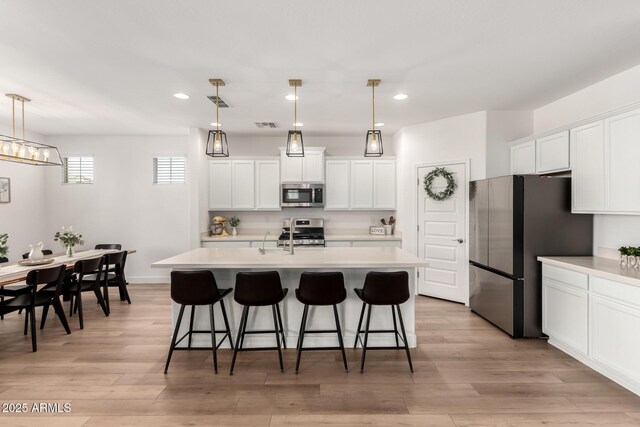 10956 E Thunderbolt Ave, Mesa, AZ 85212 - kitchen featuring appliances with stainless steel finishes, light countertops, a kitchen bar, light wood finished floors, and recessed lighting