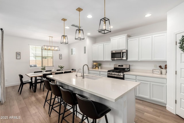 10956 E Thunderbolt Ave, Mesa, AZ 85212 - kitchen with stainless steel appliances, a sink, a kitchen island with sink, light wood finished floors, and a breakfast bar area