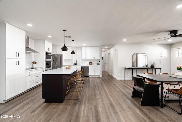 8341 E Hubbell St, Scottsdale, AZ 85257 - kitchen with stainless steel appliances, wall chimney range hood, a kitchen island, decorative backsplash, and light countertops