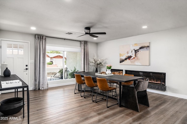 8341 E Hubbell St, Scottsdale, AZ 85257 - dining area featuring wood finished floors, a ceiling fan, recessed lighting, a glass covered fireplace, and baseboards