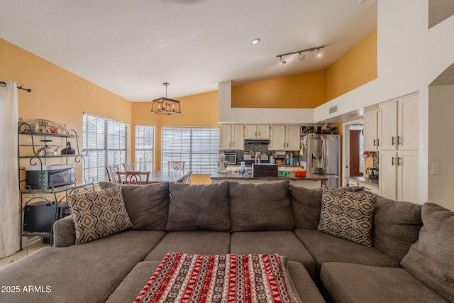 living room featuring plenty of natural light, a notable chandelier, visible vents, and high vaulted ceiling