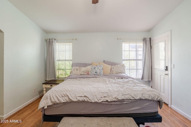 bedroom with baseboards, multiple windows, ceiling fan, and light wood-style floors