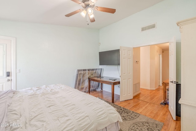 bedroom with ceiling fan, visible vents, light wood-style flooring, and vaulted ceiling