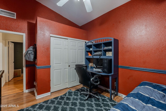 office space featuring a textured wall, visible vents, wood finished floors, and lofted ceiling