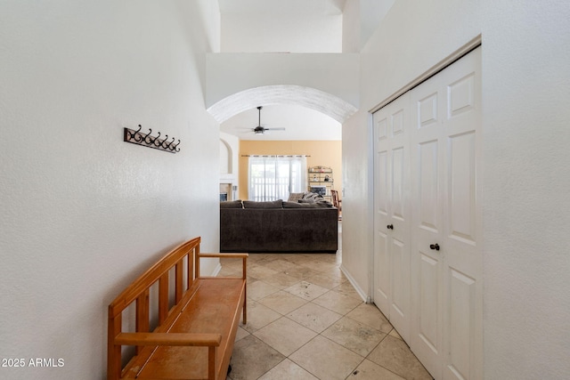 hall featuring arched walkways and light tile patterned floors
