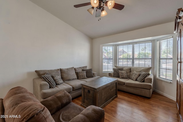 living area with wood-type flooring, ceiling fan, baseboards, and lofted ceiling