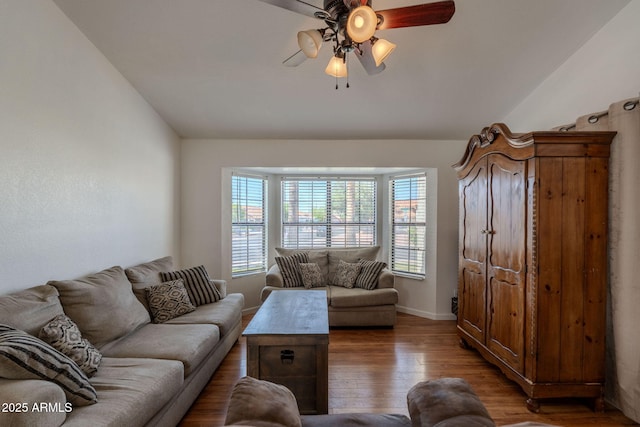 living area featuring wood-type flooring, a ceiling fan, baseboards, and lofted ceiling