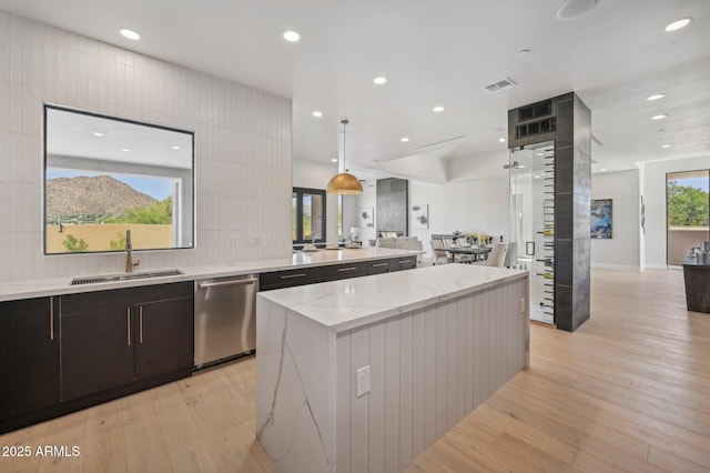 kitchen with dishwasher, a center island, pendant lighting, light stone counters, and sink