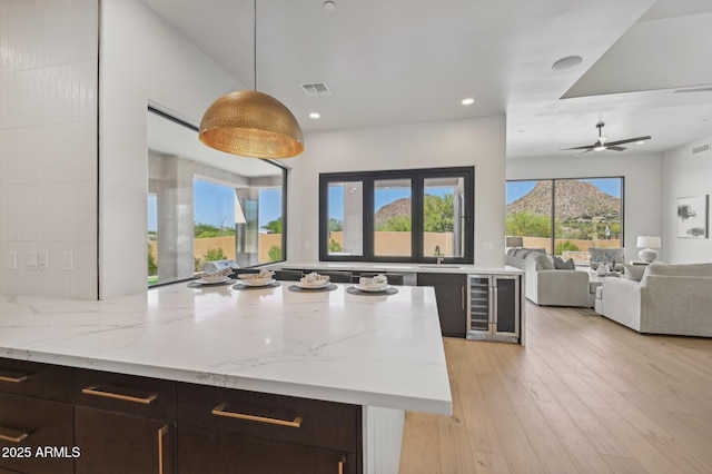 kitchen featuring sink, ceiling fan, beverage cooler, dark brown cabinets, and pendant lighting