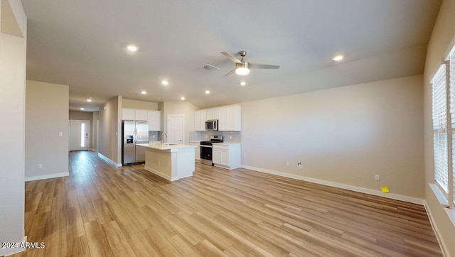 kitchen featuring appliances with stainless steel finishes, white cabinetry, a center island, tasteful backsplash, and light wood-type flooring