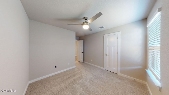 unfurnished bedroom featuring multiple windows, light carpet, and ceiling fan