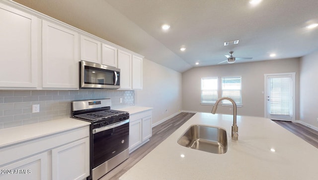 kitchen with sink, white cabinetry, tasteful backsplash, vaulted ceiling, and appliances with stainless steel finishes