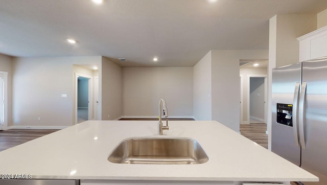 kitchen with stainless steel refrigerator with ice dispenser, sink, dark hardwood / wood-style flooring, and a kitchen island with sink