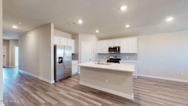 kitchen featuring appliances with stainless steel finishes, an island with sink, sink, white cabinets, and backsplash