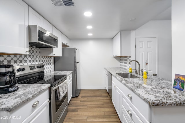 1032 E Redfield Rd, Tempe, AZ 85283 - kitchen with appliances with stainless steel finishes, dark wood-type flooring, backsplash, white cabinetry, and light stone countertops