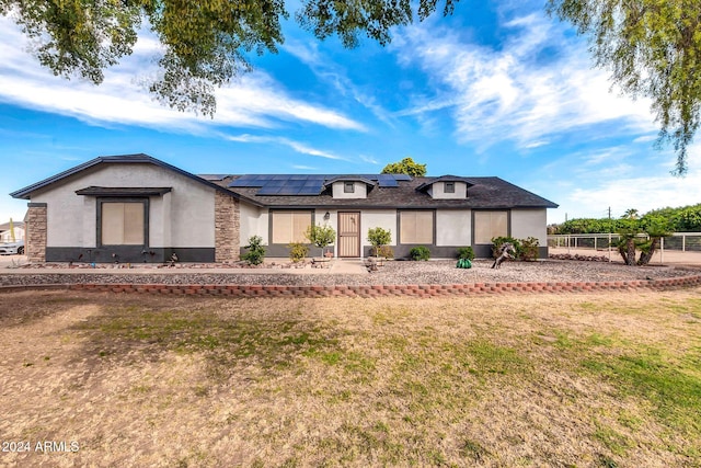 view of front of property featuring a front lawn and solar panels