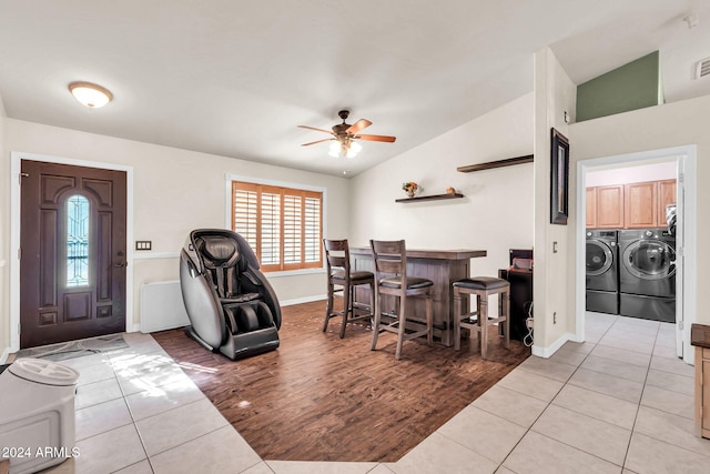 interior space featuring vaulted ceiling, washer and clothes dryer, indoor bar, ceiling fan, and light wood-type flooring