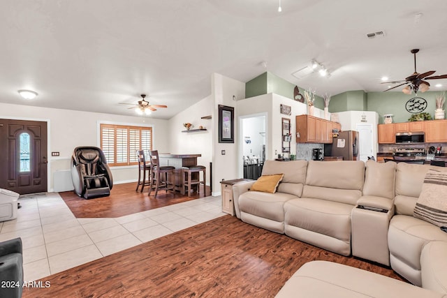 tiled living room with ceiling fan and lofted ceiling