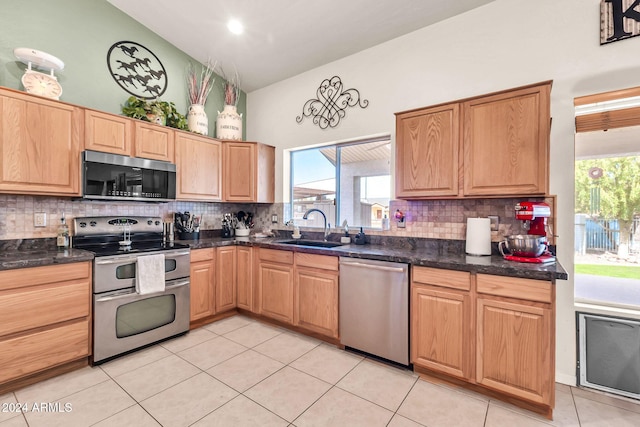 kitchen with light tile patterned flooring, backsplash, appliances with stainless steel finishes, sink, and lofted ceiling