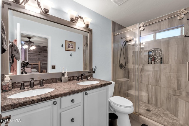 bathroom featuring toilet, a shower with door, a textured ceiling, vanity, and ceiling fan